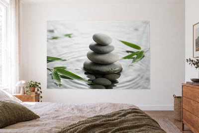 Tenture pierres zen et bambou dans une chambre claire face au lit, une commode en bois à droite – gris et vert