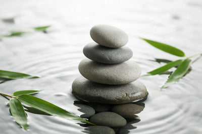 Pierres zen empilées sur une eau calme, feuilles de bambou sur les côtés, tenture murale imprimée sur tissu – gris et vert